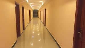 A long, narrow hallway with doors on both sides and a shiny, reflective floor. - Qingyuan Dongguan Fengxiang Hotel (Lianzhou)