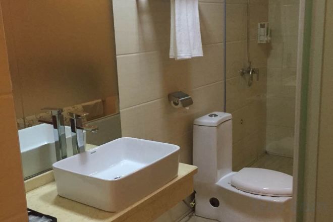 A bathroom with a rectangular sink, toilet, and glass shower enclosure.