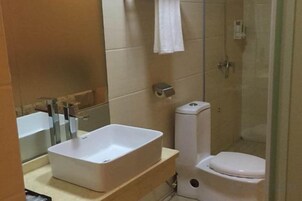 Un baño con lavamanos rectangular, inodoro y cabina de ducha con mampara de vidrio.