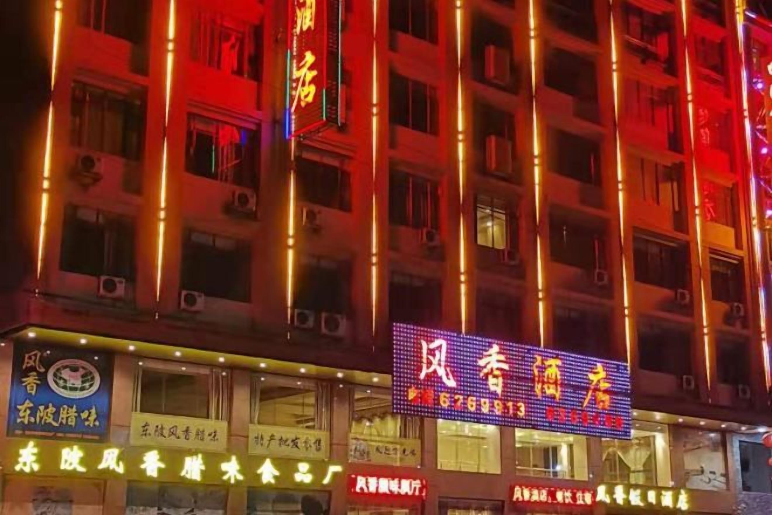 Un hotel de varios pisos con letreros iluminados y varias tiendas a nivel de calle.