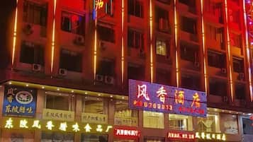 A multi-story hotel with illuminated signage and multiple ground-level shops.