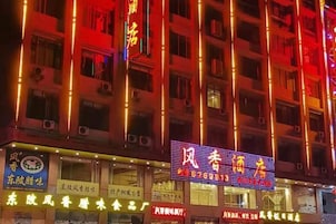 Un hotel de varios pisos con letreros iluminados y varias tiendas a nivel de calle.