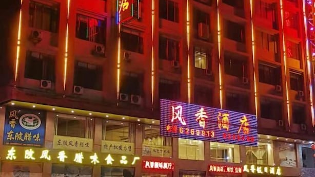 A building with multiple illuminated signs, including one with a phone number and another with Chinese characters. - Qingyuan Dongguan Fengxiang Hotel (Lianzhou)