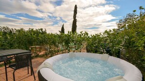An outdoor hot tub surrounded by lush greenery and a patio table. - Residence Corte Bellebarbe - Il Volto (rivoli veronese)