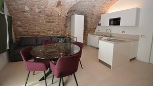 A compact kitchen with a stone ceiling, a dining table with chairs, and a small sofa. - Residence Corte Bellebarbe - Il Volto (rivoli veronese)