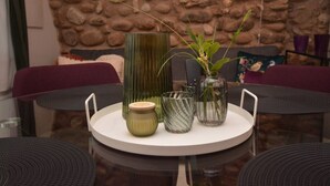 A round table with a white tray holding three glass vases and a ceramic jar, set against a stone wall backdrop. - Residence Corte Bellebarbe - Il Volto (rivoli veronese)