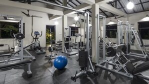 Ein Fitnessstudio mit unterschiedlichen Trainingsgeräten, darunter Kraftgeräte, eine Bank und eine große Trainingskugel.