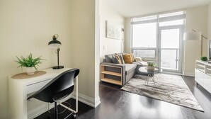 Een moderne woonkamer met een bureau, een bank en een groot raam.