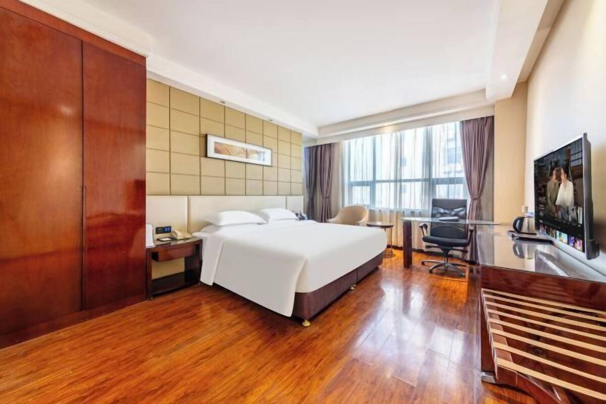 Une chambre d’hôtel avec un grand lit, un bureau, une chaise, une télévision et une armoire.