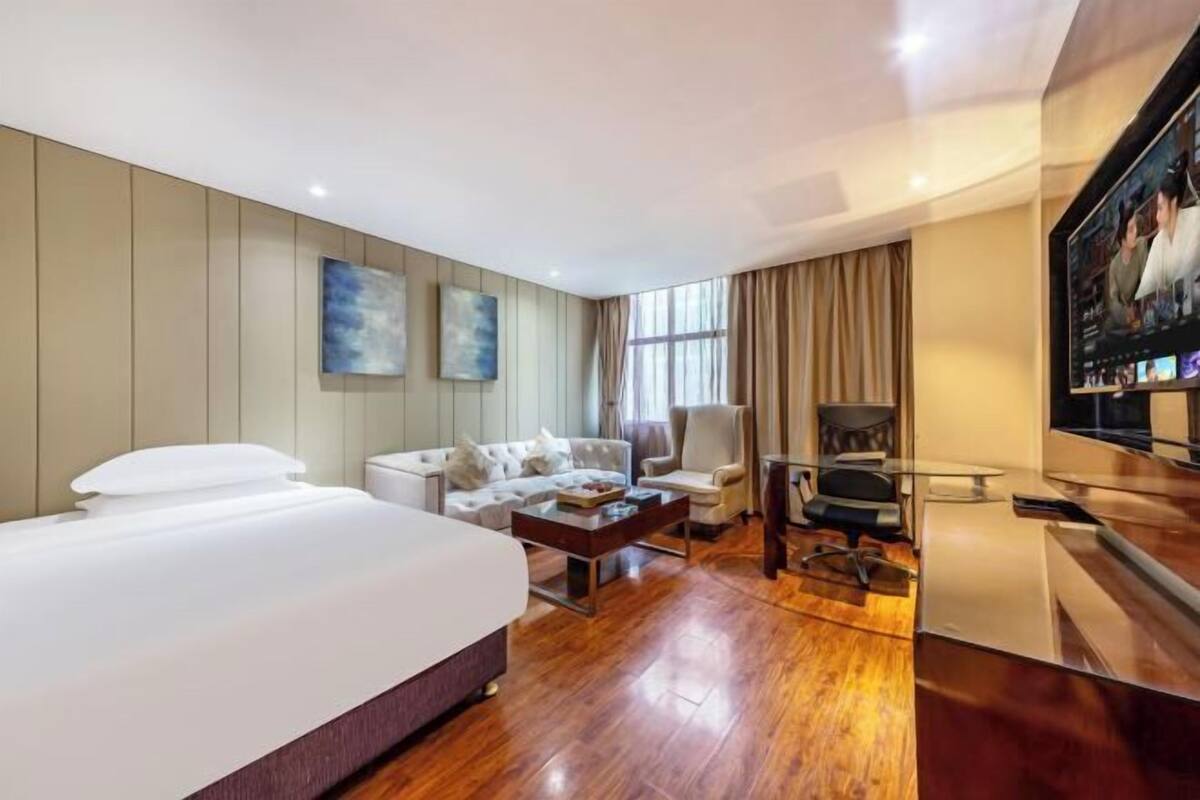 Une chambre d’hôtel avec un grand lit, un canapé, une table basse, un bureau et un téléviseur.