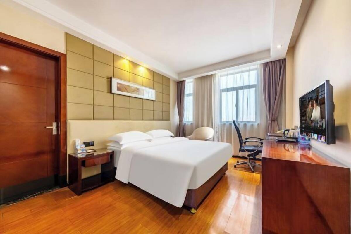 Une chambre d’hôtel comprenant un lit, une table de chevet, une chaise, un bureau et un téléviseur.