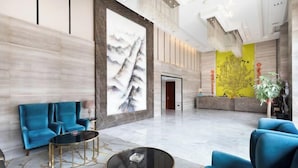 A spacious lobby with a large abstract painting, a reception desk, and seating areas. - Wan Yue Hotel (Jinjiang)