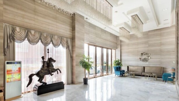 A spacious lobby with a marble floor, a large window with curtains, a statue, and a seating area with blue chairs. - Wan Yue Hotel (Jinjiang)