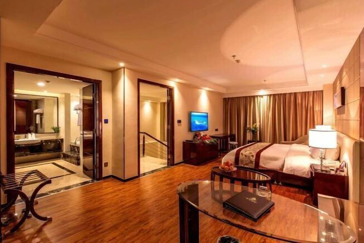 Une chambre d’hôtel équipée d’un lit, d’une table de chevet, d’une lampe, d’une télévision et offrant une vue sur la salle de bain.