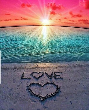 En strand med ordet "LOVE" og et hjerte tegnet i sandet.