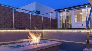 Une terrasse agrémentée d’un foyer, d’un mur en briques et d’une porte vitrée donnant sur une pièce.