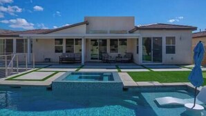 Une maison moderne dotée d’une piscine, de grandes fenêtres et d’un espace patio.