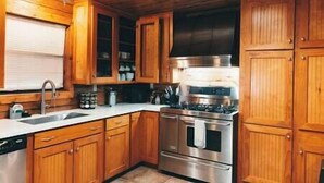 Una cocina con gabinetes de madera, estufa de acero inoxidable y una ventana sobre el fregadero.