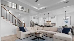 Ein geräumiges Wohnzimmer mit einer großen Eckcouch, einem Couchtisch und einer Treppe, die zu einer oberen Etage führt.