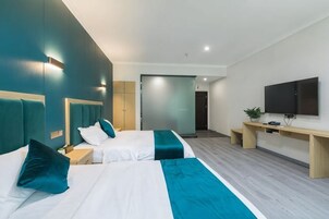 Una habitación de hotel moderna con dos camas, un escritorio, un televisor y una puerta corredera que da al baño.