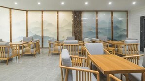 A modern interior with wooden furniture, a large table, and a view of mountains through a glass wall. - Yading Boutique Hotel (Meishan Sansuxuan) (Meishan)