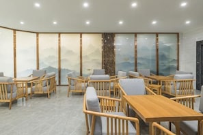 A modern interior with wooden furniture, a large table, and a view of mountains through a glass wall. - Yading Boutique Hotel (Meishan Sansuxuan) (Meishan)