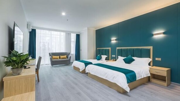 A modern hotel room with two beds, a desk, a chair, a potted plant, and a view of the city. - Yading Boutique Hotel (Meishan Sansuxuan) (Meishan)