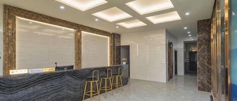 A reception area with a marble counter, a reception desk, and a seating area with chairs.