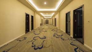 A hotel hallway with a patterned carpet, doors on both sides, and a ceiling light. - Yading Boutique Hotel (Meishan Sansuxuan) (Meishan)