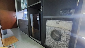 A compact kitchen with a refrigerator, sink, and a small countertop. - Studio Pollux Sea View Apartments

 (Batam City)