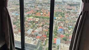 A room with a large window overlooking a cityscape. - Studio Pollux Sea View Apartments

 (Batam City)