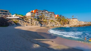 A beachfront hotel with multiple stories, a sandy beach, and rocky cliffs. - Oceanfront, Gound floor, Steps to the Beach!  (Cabo San Lucas)