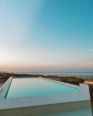 A rectangular swimming pool with a clear view of the sea and distant buildings. - So City Hotel - Adults Only (St. Julian's)
