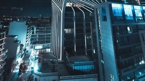 A modern high-rise building with a unique architectural design, featuring a prominent vertical structure and illuminated lines. - So City Hotel - Adults Only (St. Julian's)