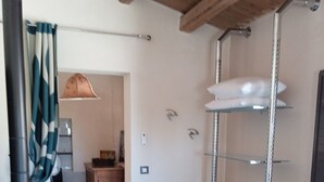 A room with a tiled floor, a black heater, a glass shelf unit, and a white chair. - Characteristic olive grove (Noto)