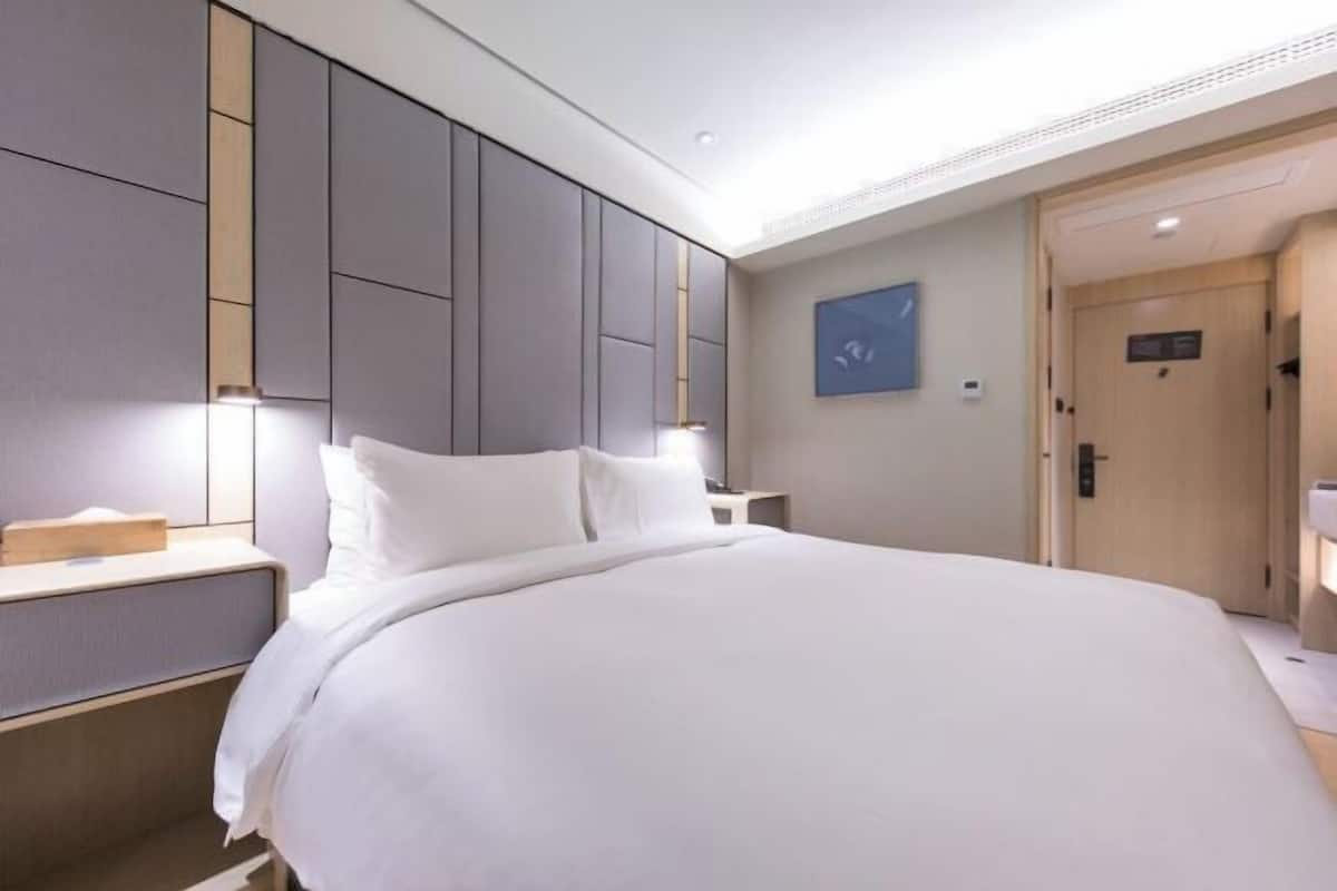 Una habitación de hotel moderna con una cama grande, una mesita de noche y un armario.