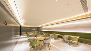 Ein modernes Restaurant mit minimalistischem Design, mit grünen Sitzgelegenheiten und einem großen Fenster mit Blick auf die Berge.
