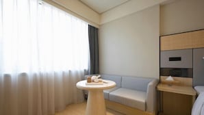Ein modernes Hotelzimmer mit rundem Tisch, einer Couch und einem Bett.