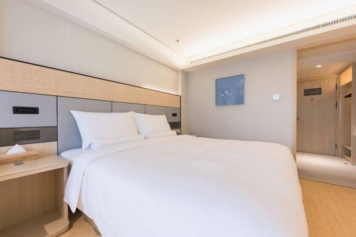 Una habitación de hotel moderna con una cama grande, una mesita de noche y una obra de arte colgada en la pared.