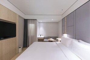 A modern hotel room with a large bed, a flat-screen TV, a small table, and a bedside table with a lamp. - JI Beijing National Stadium-Bird's Nest Guanzhuang Subway Station Hotel (Beijing)