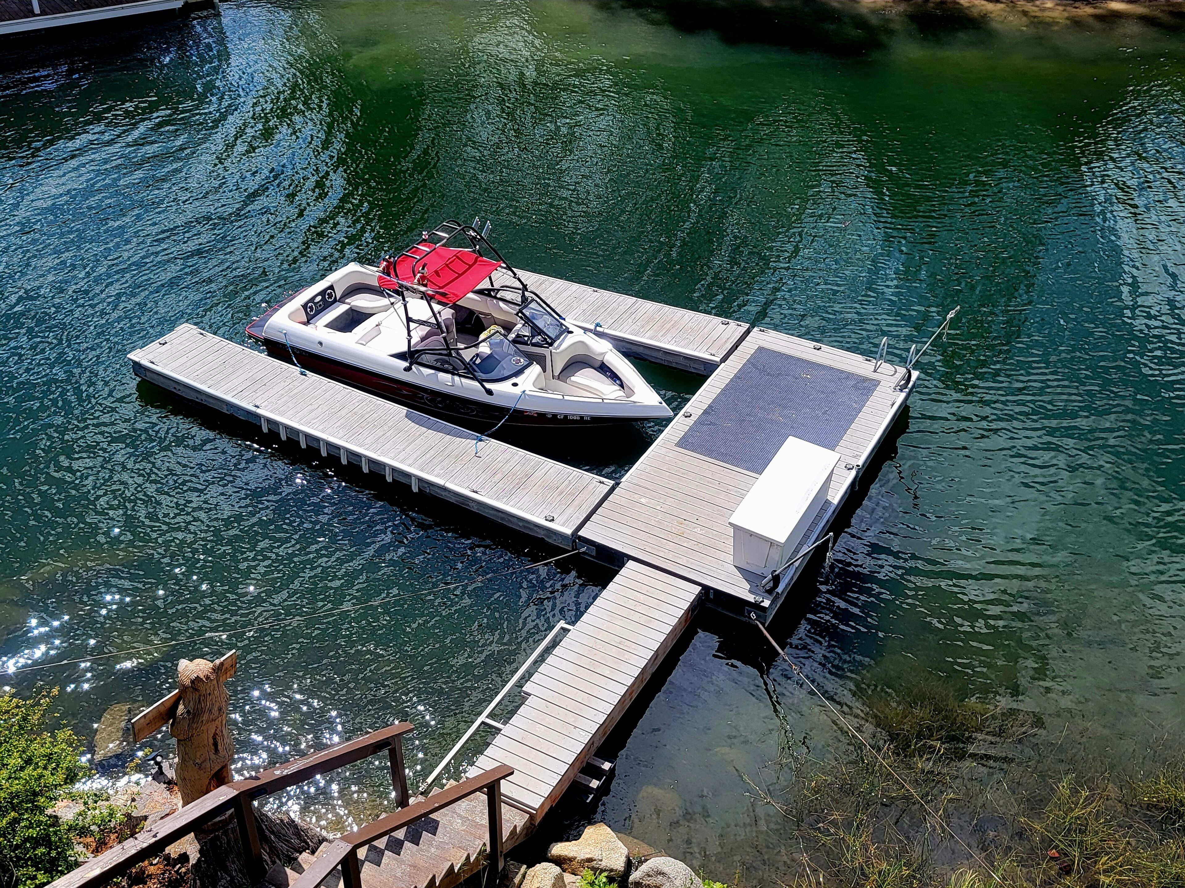 Un bateau était amarré à une jetée en bois qui s’étendait sur une étendue d’eau.