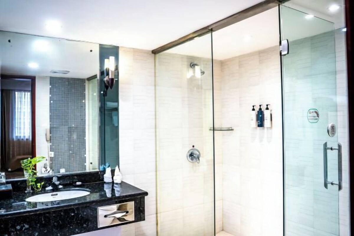 A modern bathroom with a glass shower enclosure, a marble sink, and a large mirror.