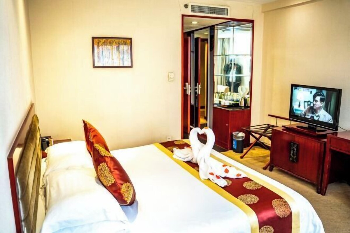 Ein Hotelzimmer mit einem Bett, einem Fernseher, einem Schreibtisch und einem Kleiderschrank.