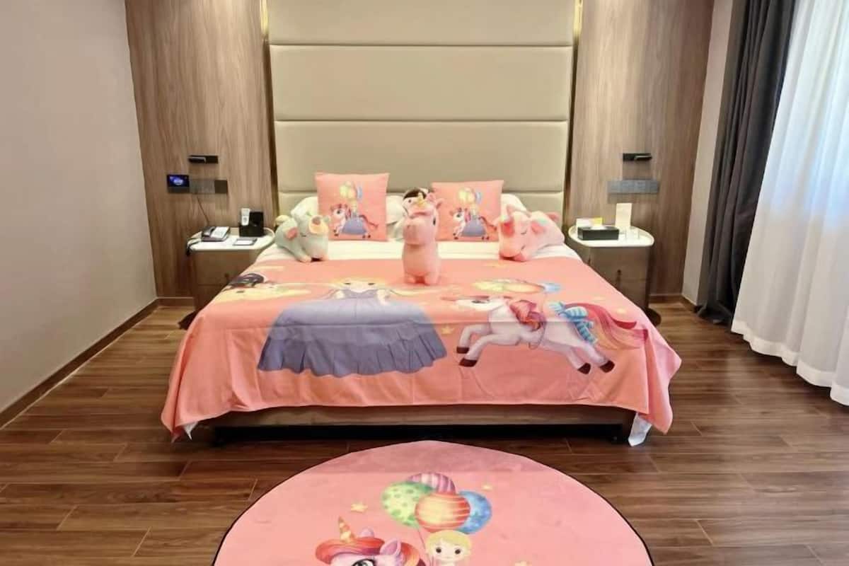 A hotel room with a large bed, a bedside table, a nightstand, and a round rug.