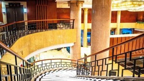 Un intérieur à plusieurs niveaux, doté d’un escalier en colimaçon, d’un sol en marbre et d’un design moderne agrémenté d’éléments en bois et de rampes en métal.
