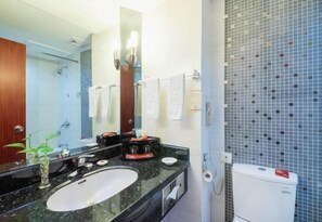 Ein Badezimmer mit großem Spiegel, Waschbecken, Toilette und Dusche.