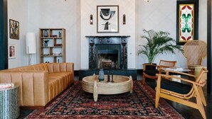 A living room with a sofa, a round wooden coffee table, a fireplace, and a large plant. - Inn at Gough (San Francisco)