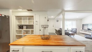 A modern kitchen with a wooden countertop, white cabinetry, and a built-in bookshelf. - Entire Home Away From Home (Meridian)