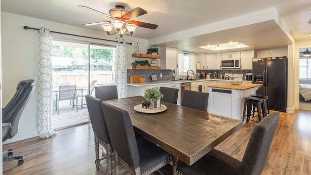 A modern kitchen with a central island, a dining area with a wooden table and chairs, and a ceiling fan. - Entire Home Away From Home (Meridian)