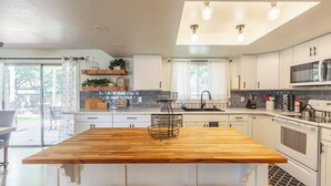 A modern kitchen with a central island, white cabinetry, and a large window providing natural light. - Entire Home Away From Home (Meridian)